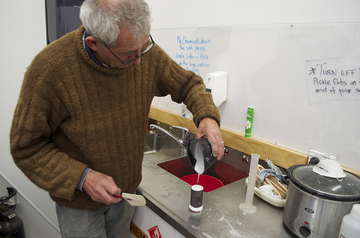Pouring plaster mix into tin, over wax carving.